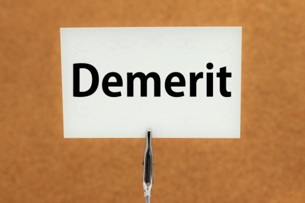 「Demerit」と書かれた紙がコルクボードに固定されている画像