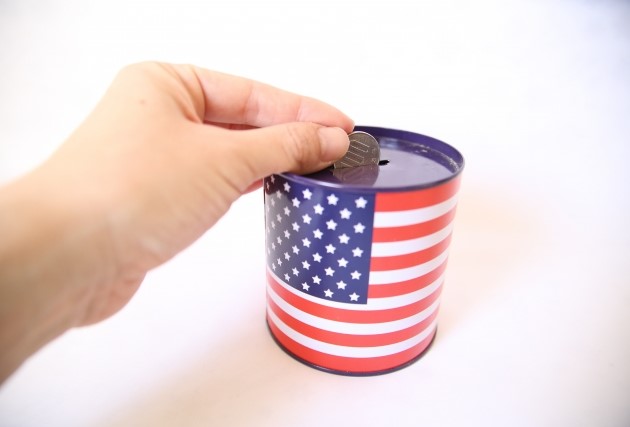 アメリカ国旗が描かれた貯金箱に100円を入れている画像