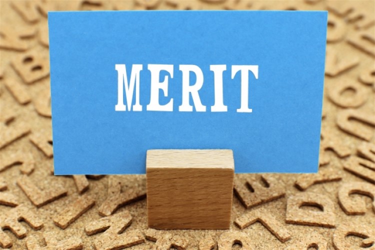 「MERIT」と書かれた青紙が木片で自立している画像
