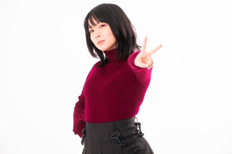 腰に手をやり反対の手でピースサインをする女性の画像